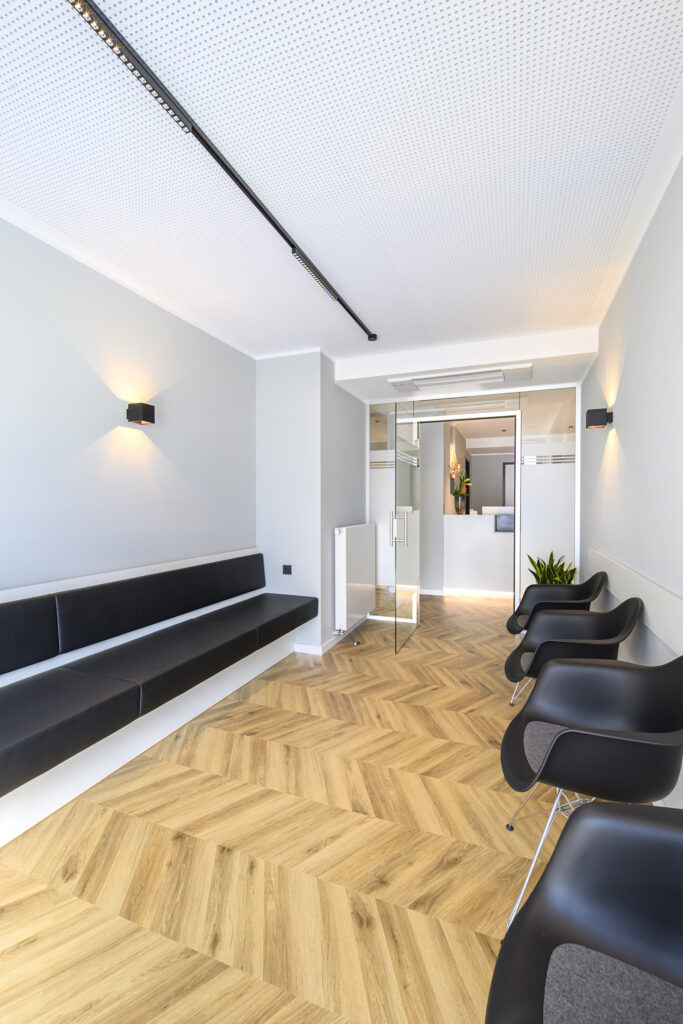 Wartebereich einer allgemeinmedizinischen Praxis mit schwarzen Stühlen.