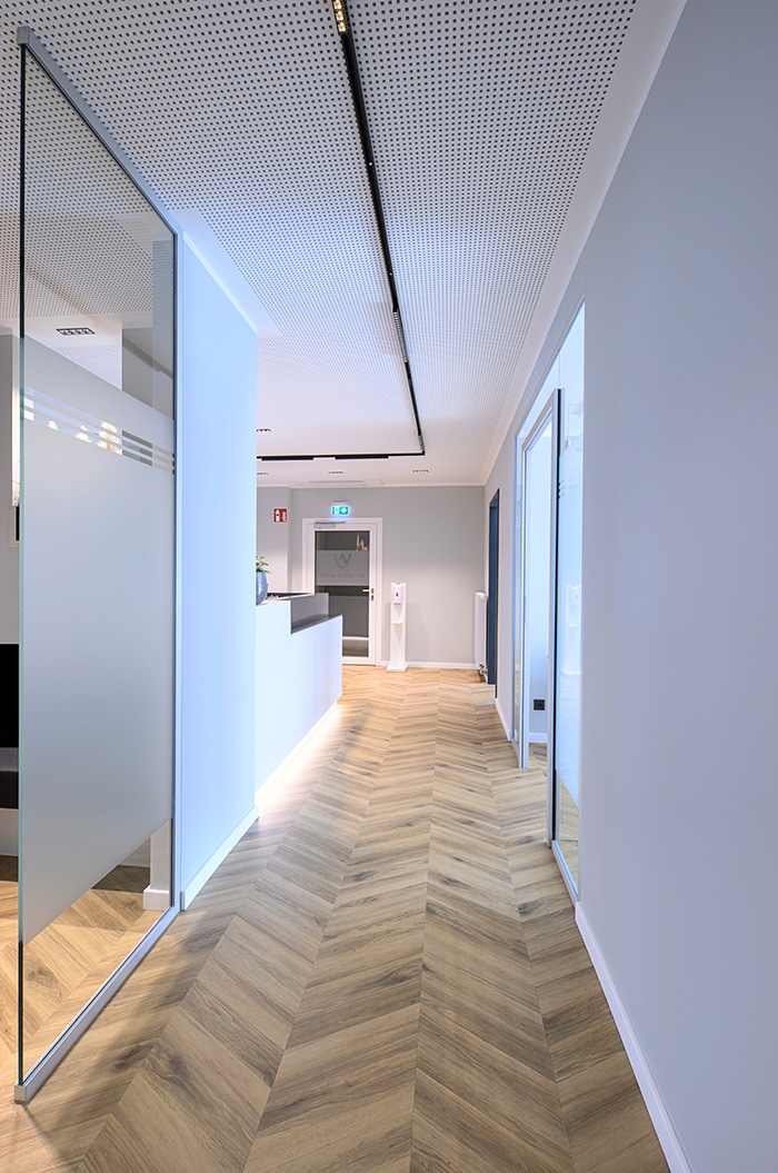 Heller moderner Flur mit Holzfussboden und weissem Tresen in einer Praxisumgebung