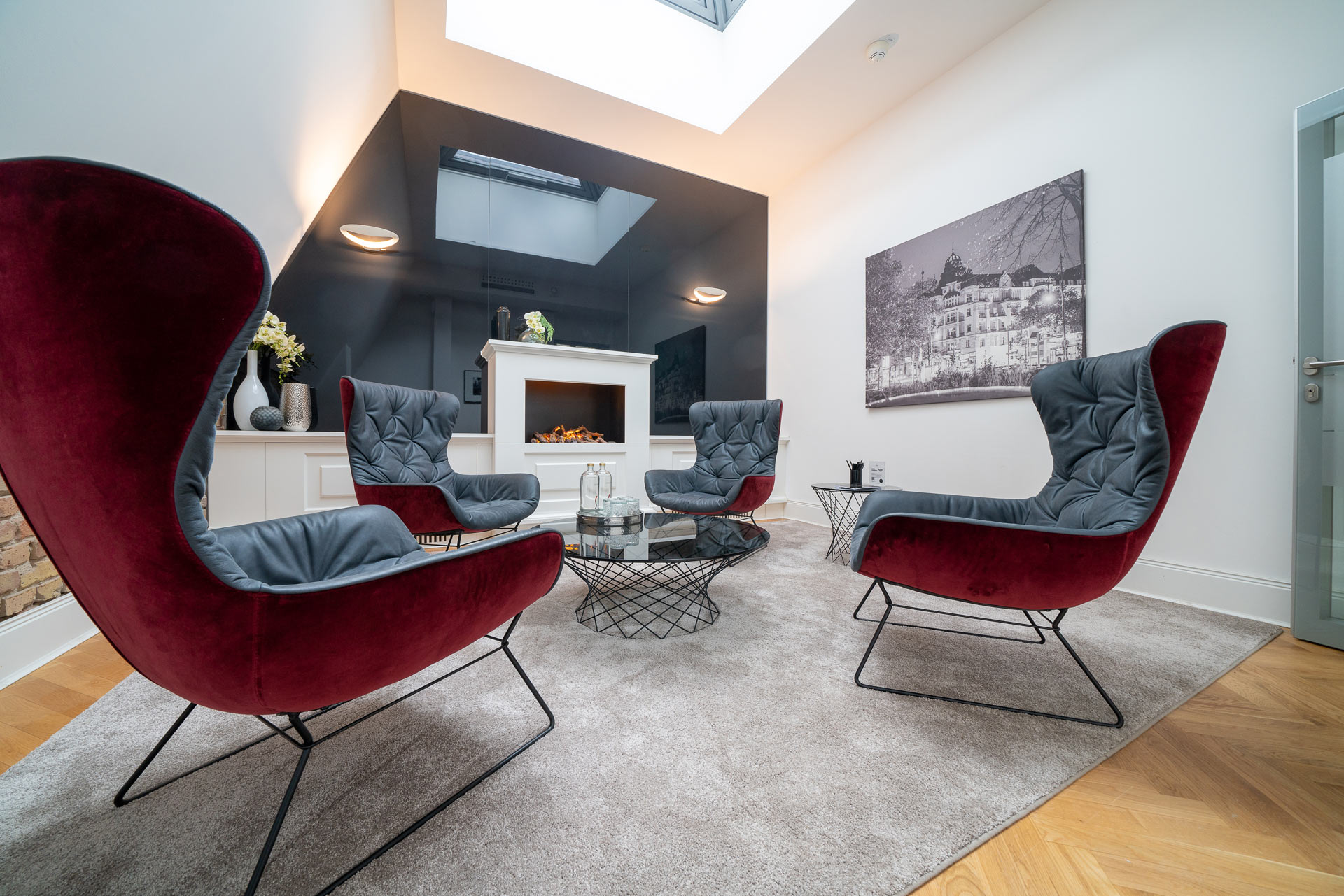 Modern Wohnzimmer mit vier samtroten Designersesseln, Kamin und großem Oberlicht