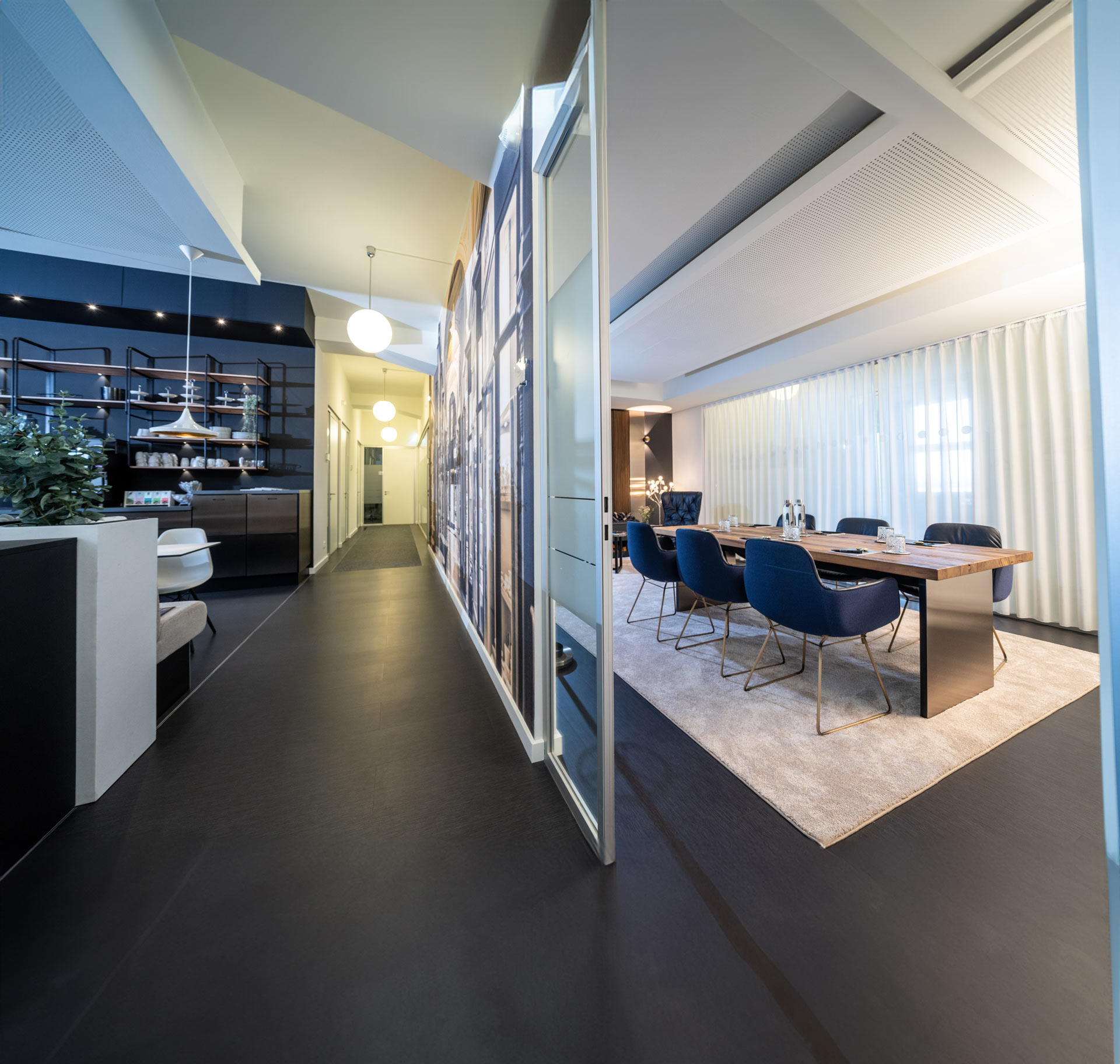 Moderner Konferenzraum mit blauen Stühlen, Holztisch und hellen Vorhängen