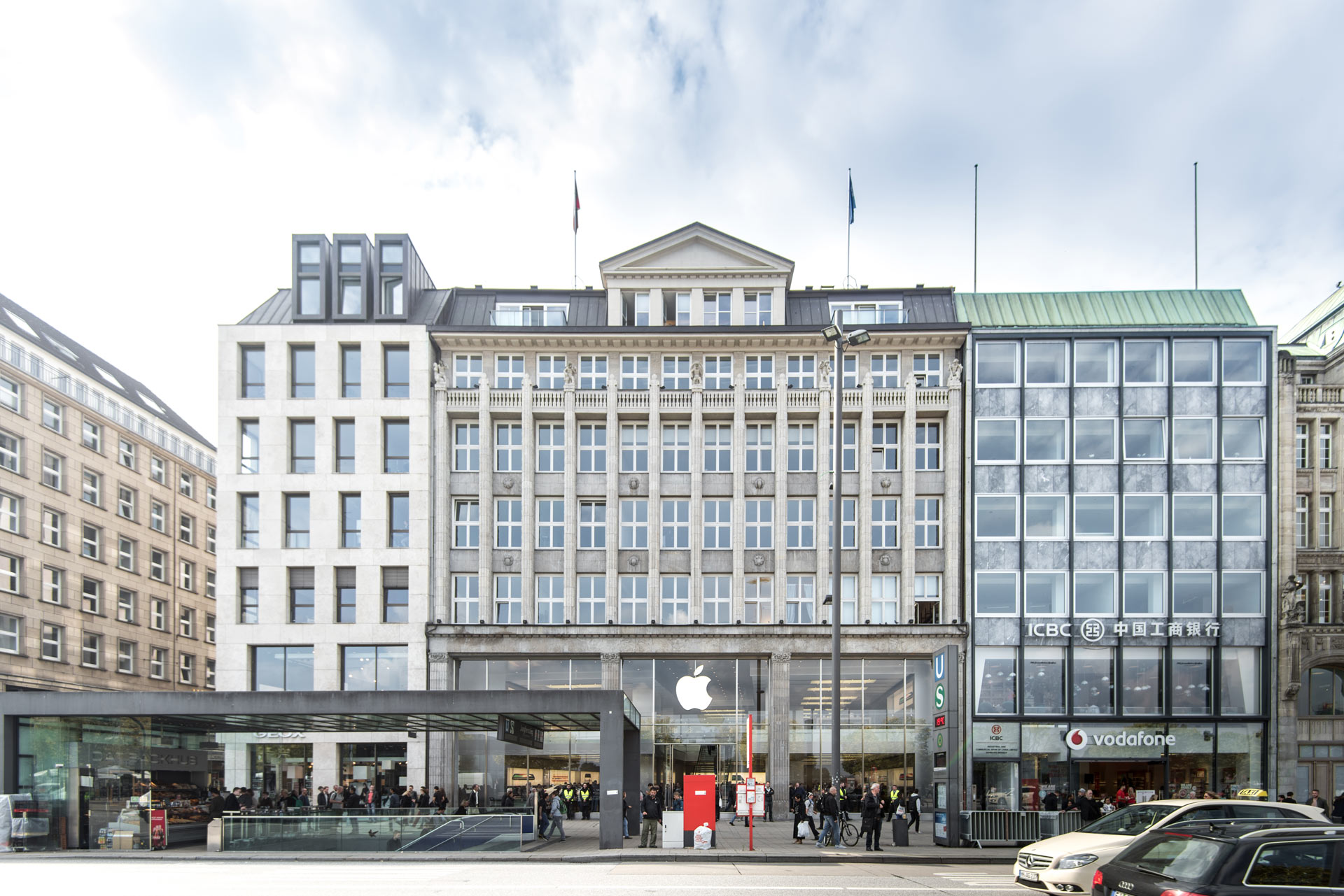 Ein großes Gebäude mit Apple Store im Erdgeschoss, viele Menschen davor und helles Tageslicht