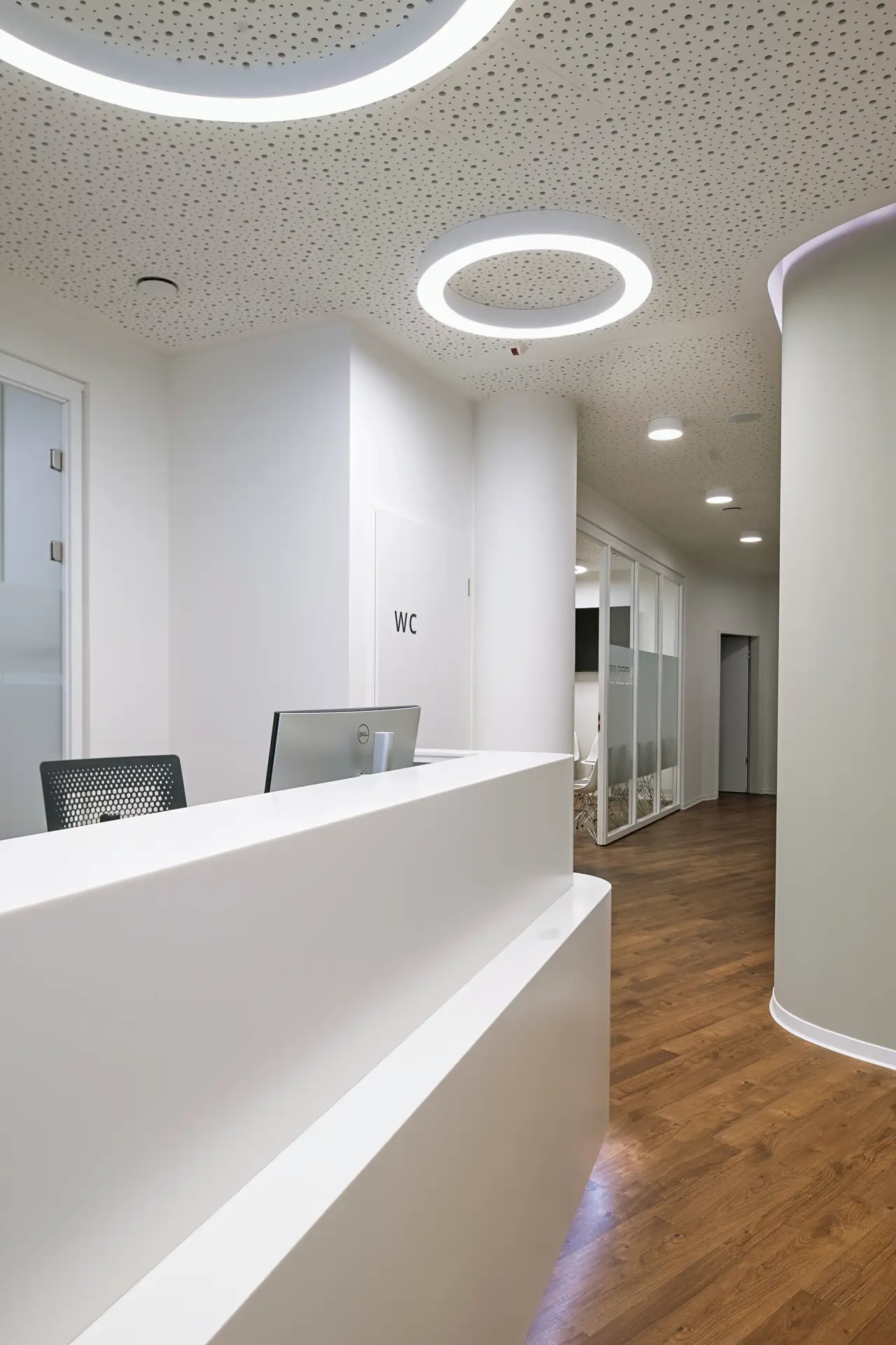 Leere weiße Rezeption mit Ringlampen, Holzfußboden und Glasflur, ruhig