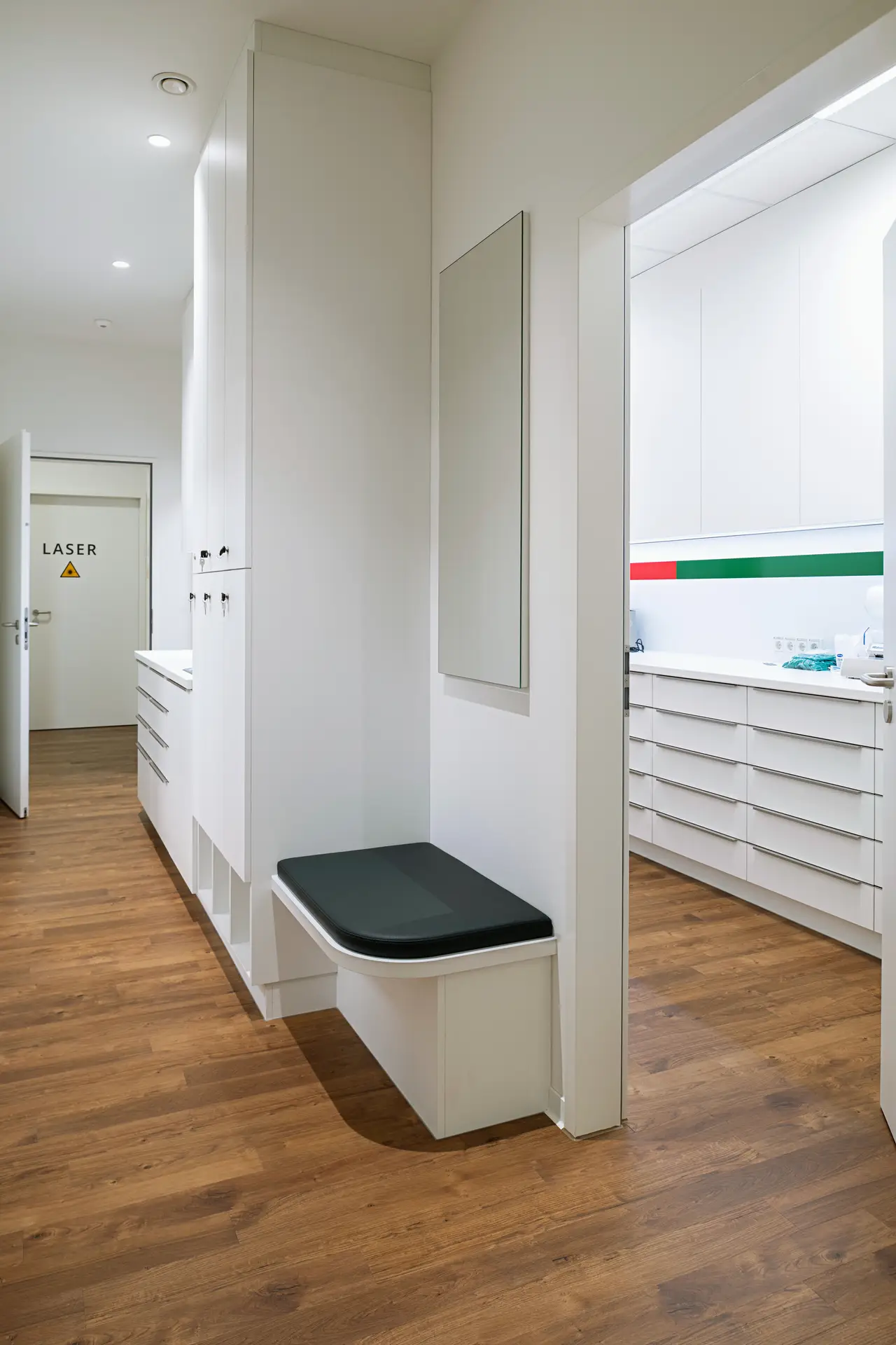 Heller Klinikflur mit weißer Einrichtung, Holzboden und Tür Laser ohne Punkt