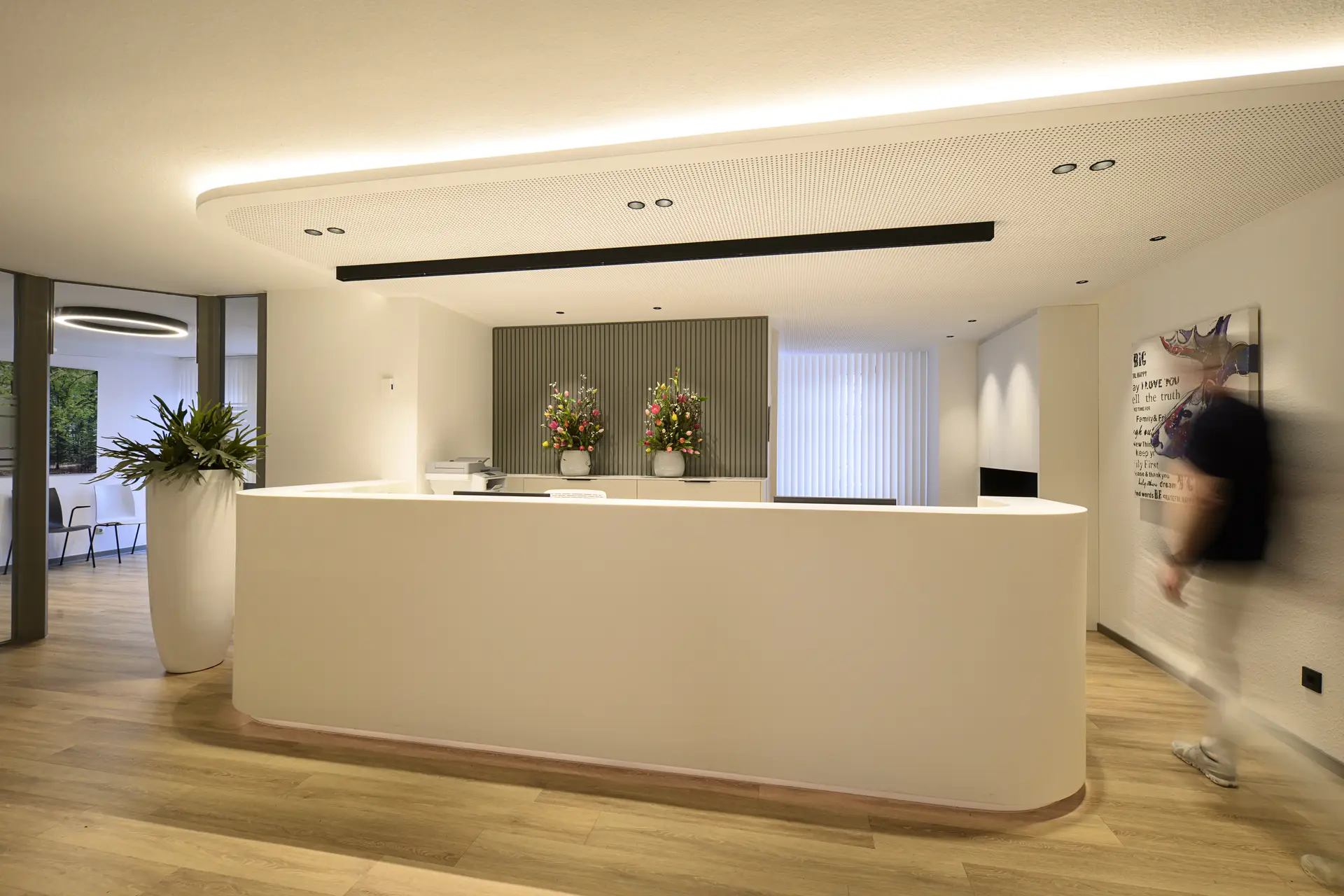 Moderne weisse Rezeption mit Blumenvasen und unscharfer Person rechts