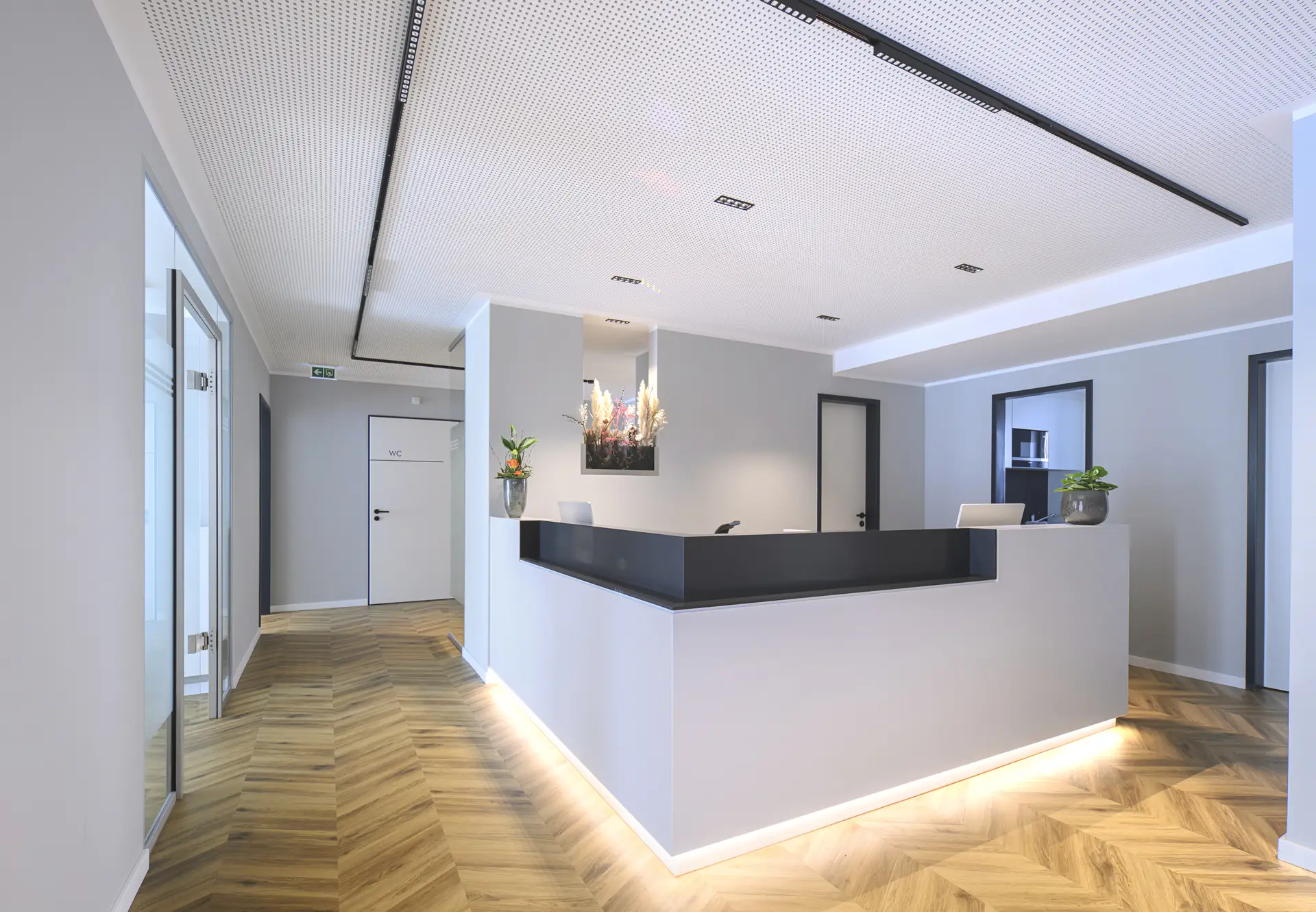 Leere Rezeption mit schwarzer Theke, helles Holz und moderne Beleuchtung