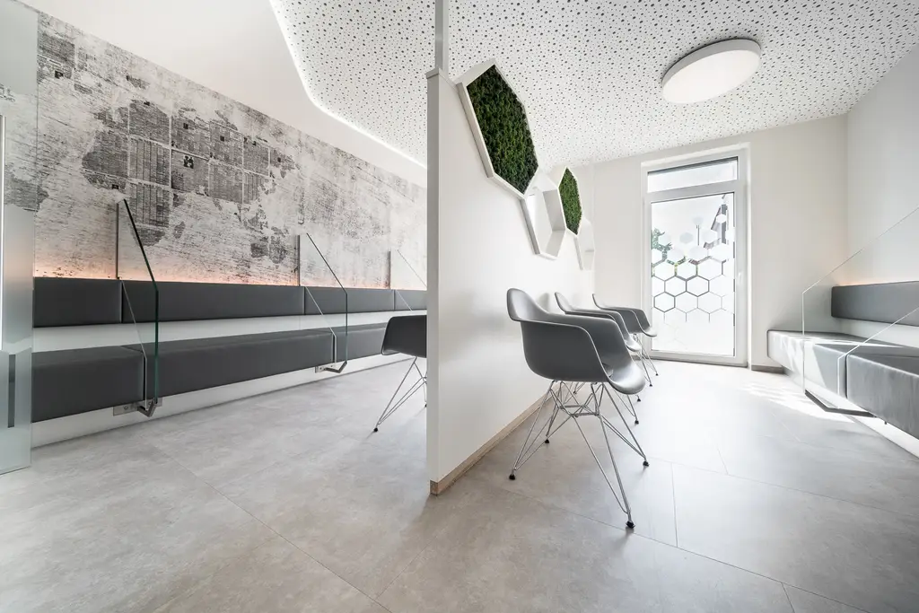 Helles Wartezimmer ohne Personen mit grauen Sitzen und grünen Wandpanelen