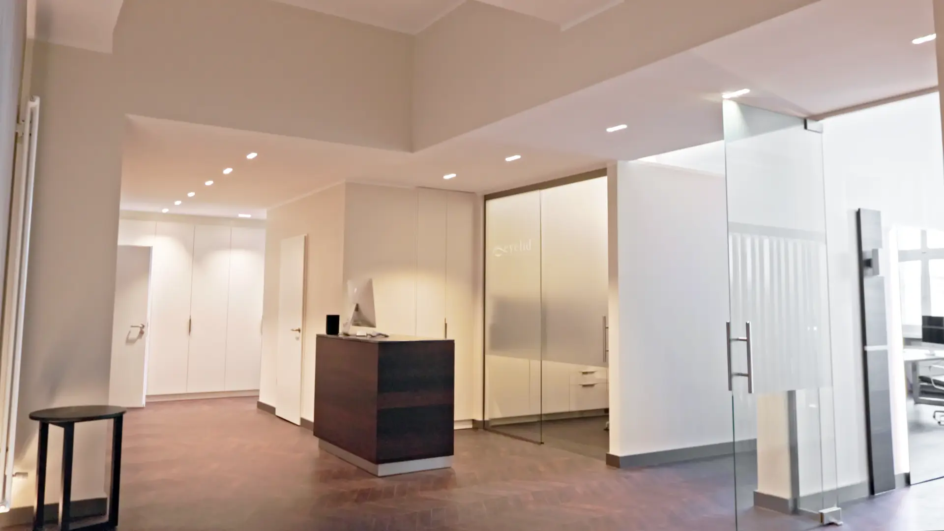 Leere moderne Lobby in Weiß und Beige mit dunklem Empfangstresen und Glaswand