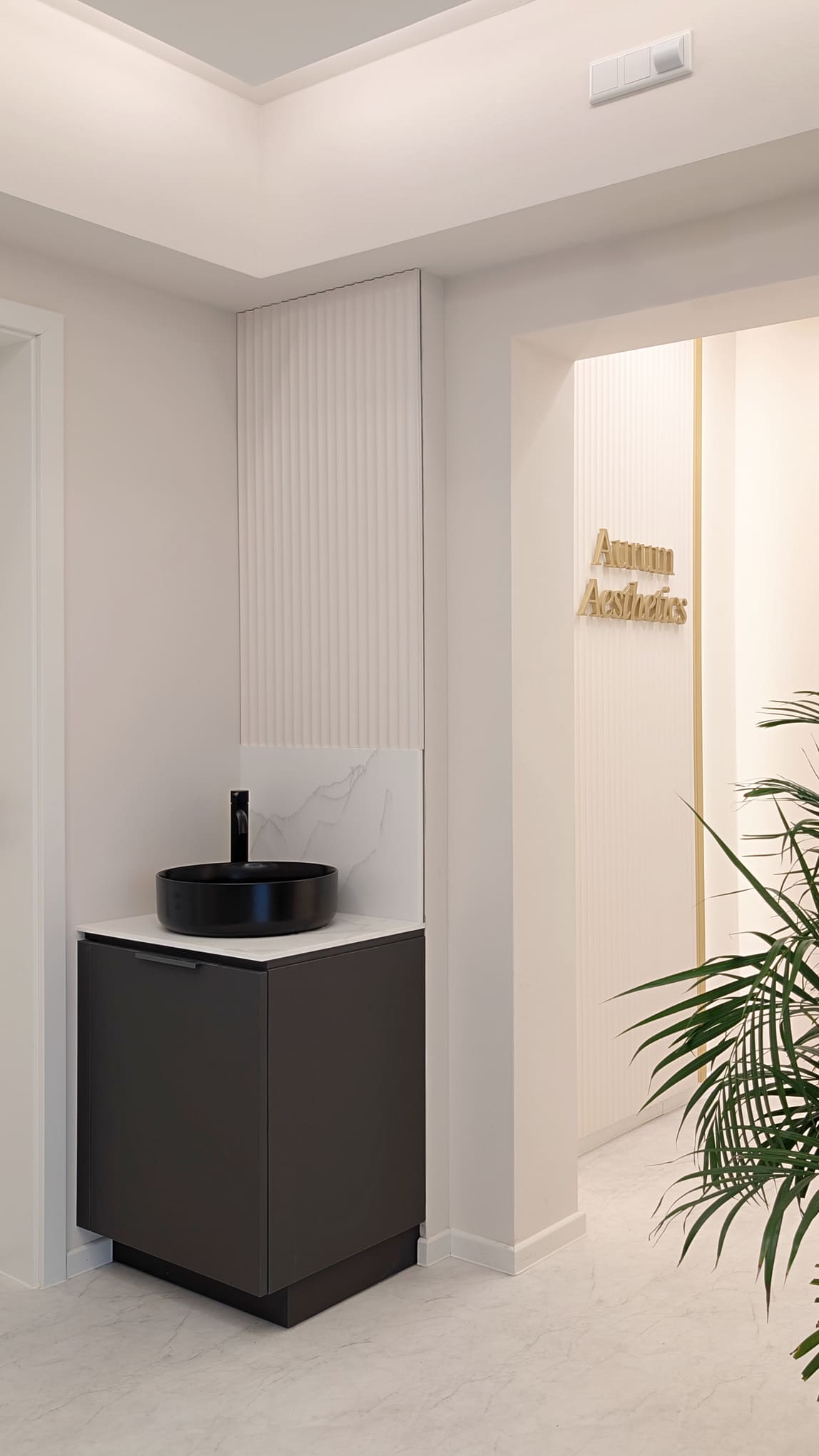 Elegantes Waschbecken in Schwarz neben goldenem Schriftzug Aurum Aesthetics